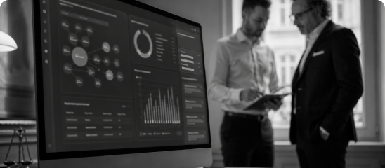 SEO-Analyse für Kanzleien: Zwei Männer besprechen sich neben einem Monitor mit Marketing-Dashboard