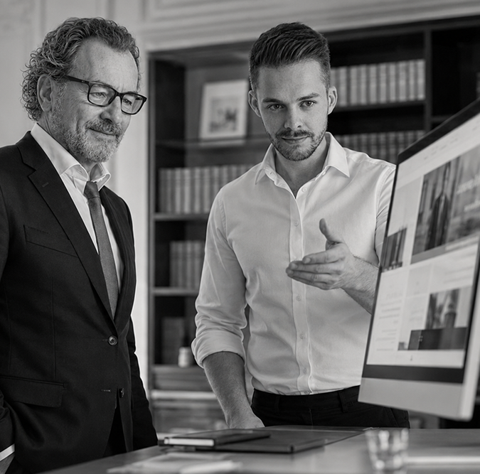 Webdesign für Rechtsanwälte: Berater präsentiert einem Anwalt die neue Kanzlei-Website am Monitor